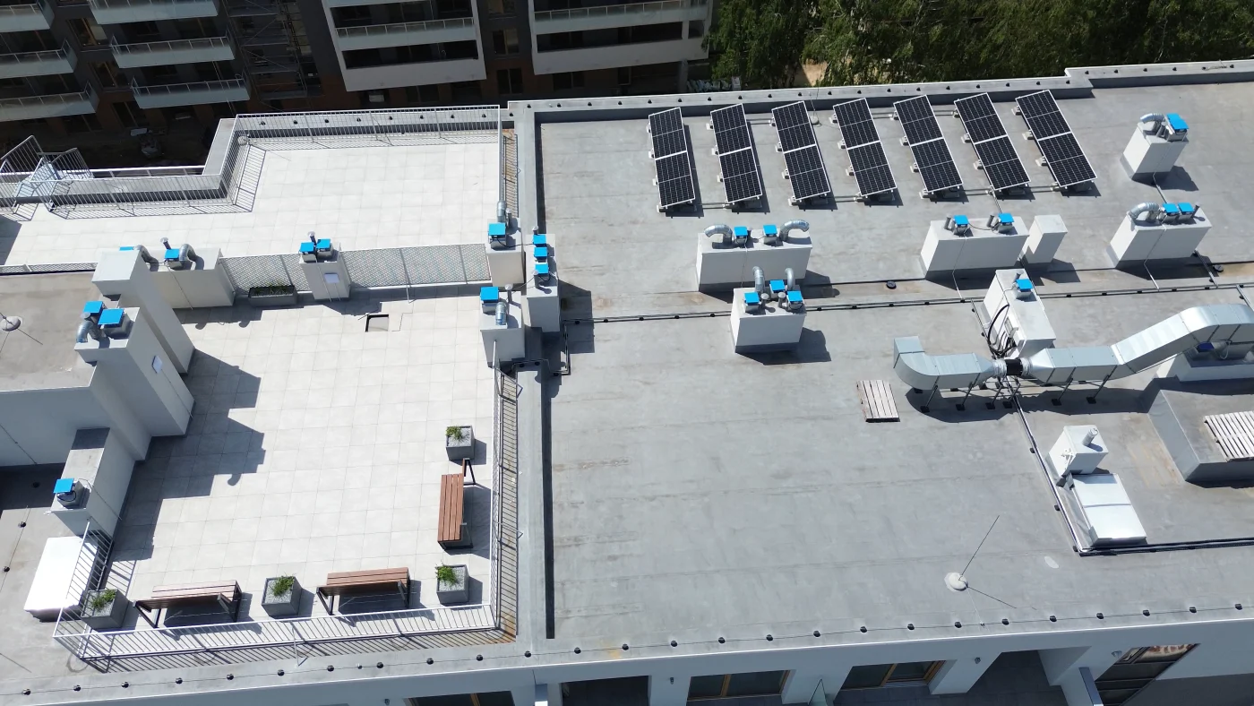 Reliable Commercial Roofing | Winter Park, FL | Universal Roof & Contracting Aerial view of a large commercial flat roof featuring multiple solar panels, HVAC units, ventilation systems, and rooftop walkways.