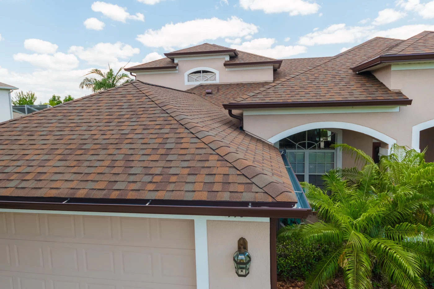 Excellent Residential Roofing Company | Westchase, FL | Universal Roof and Contracting Close-up view of a light stucco Florida home with a freshly installed multi-toned brown asphalt shingle roof above the garage.